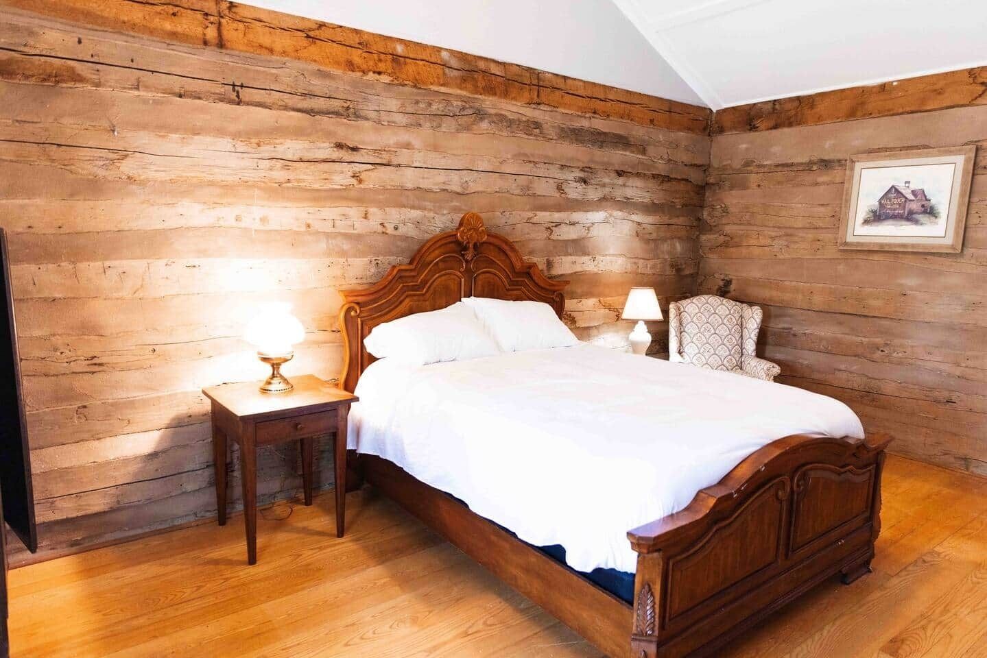 A wooden-paneled bedroom with a wooden bed, two bedside tables, and a chair.