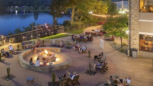 An outdoor patio area with a fire pit, seating, and a view of a lake.