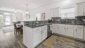 Una cocina moderna con armarios blancos, encimeras de granito y una isla central.