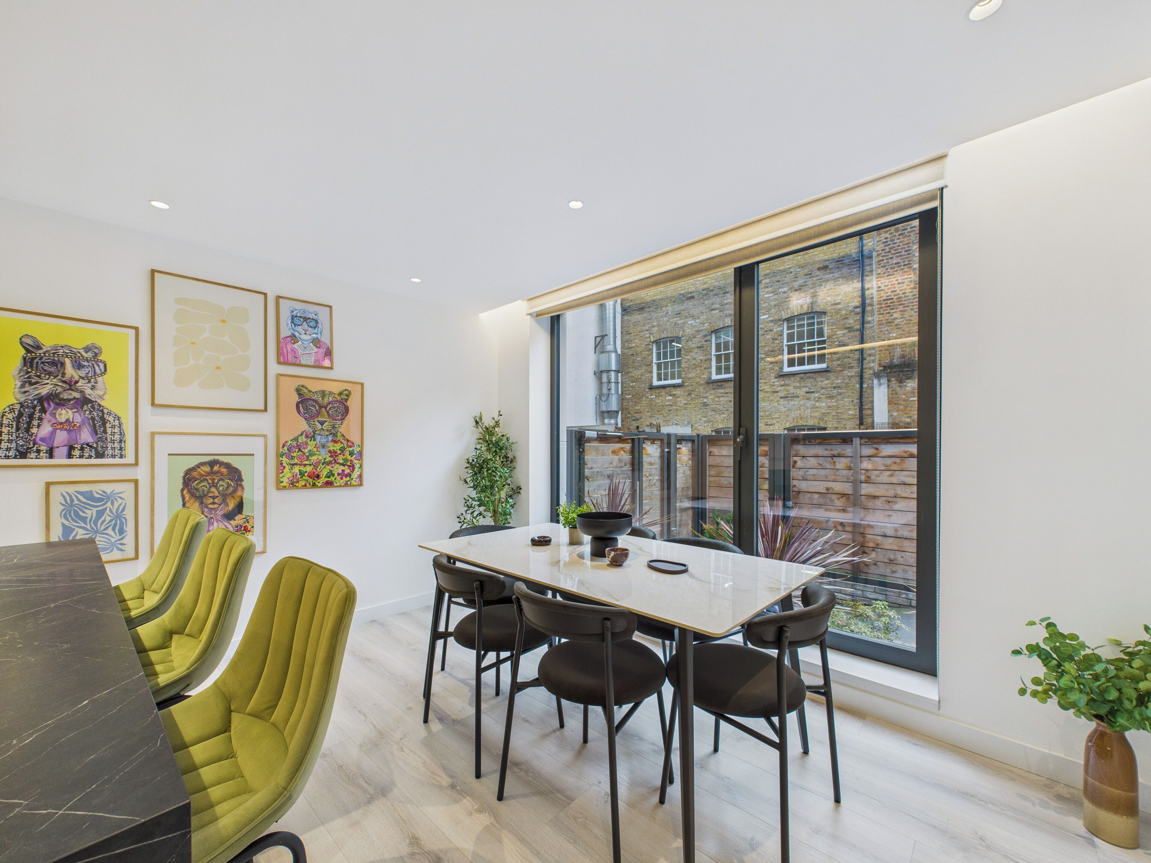 A modern dining area with a large table, chairs, and artwork on the walls.