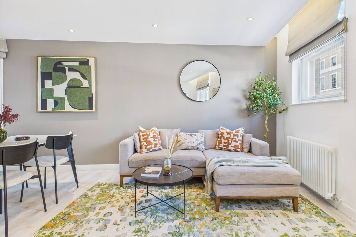 Un salon moderne avec un canapé gris, deux fauteuils, une table basse et un tapis à motifs.
