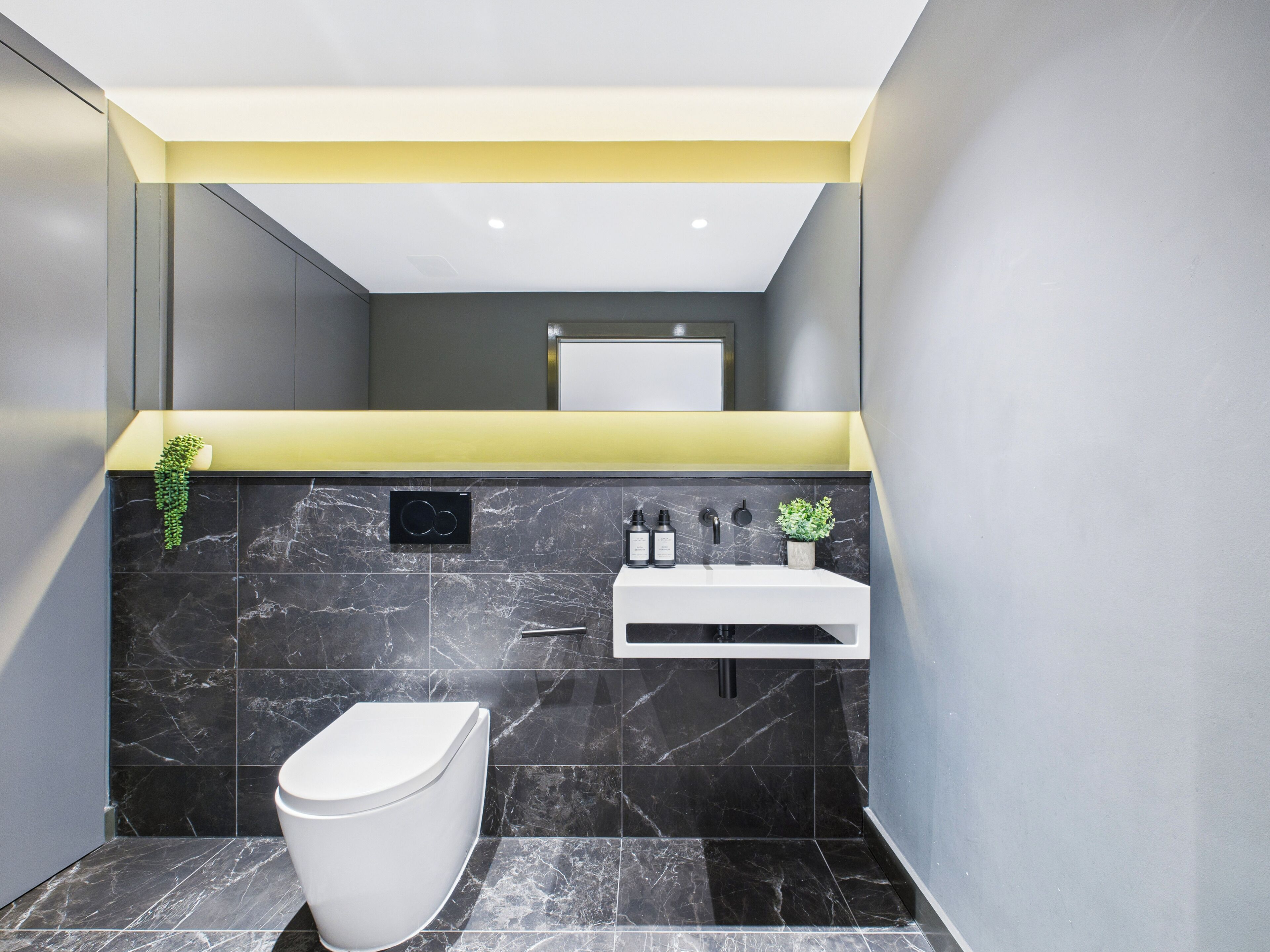Un baño moderno con inodoro, lavamanos y zona de ducha.