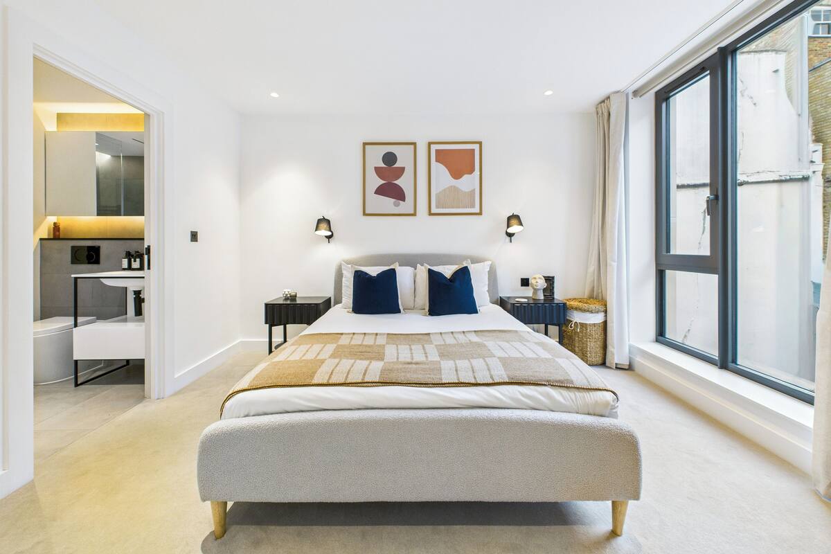 Une chambre moderne avec un grand lit, des tables de chevet, une armoire et une fenêtre donnant sur un beau paysage.
