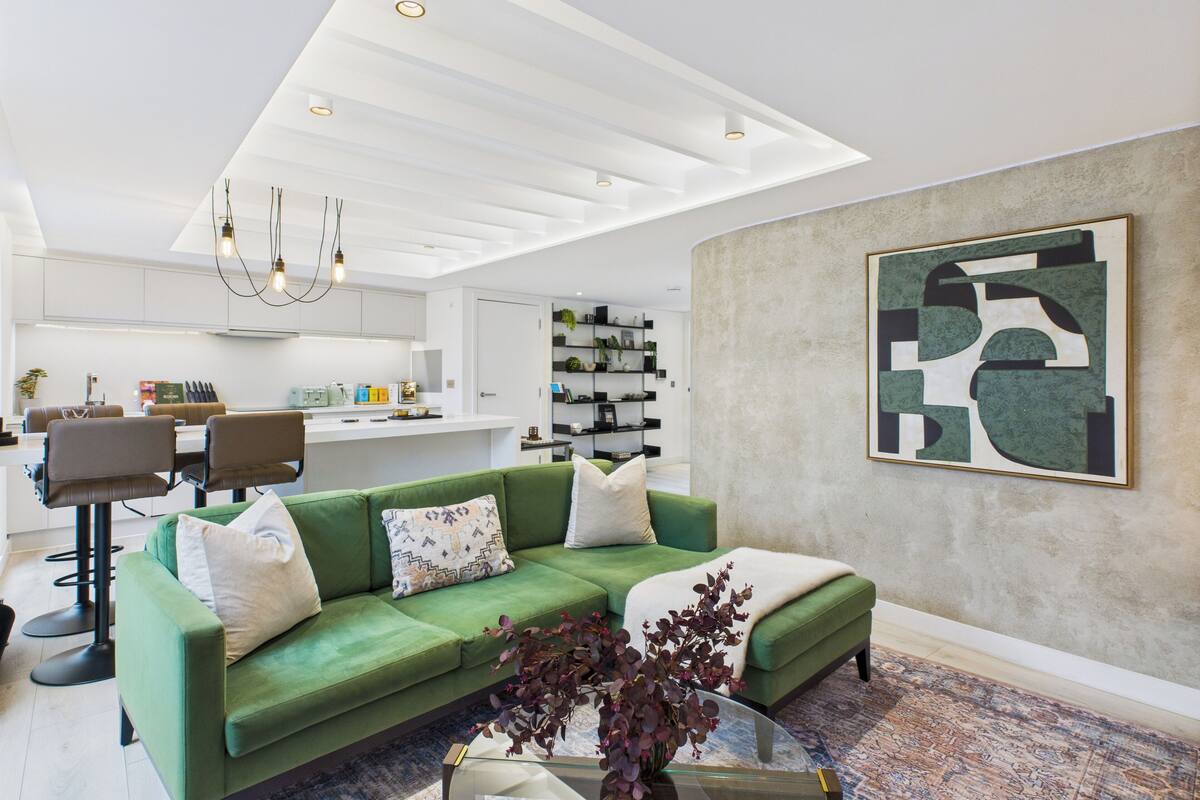 Un salon moderne avec un canapé vert, une table basse et un grand tableau abstrait accroché au mur.