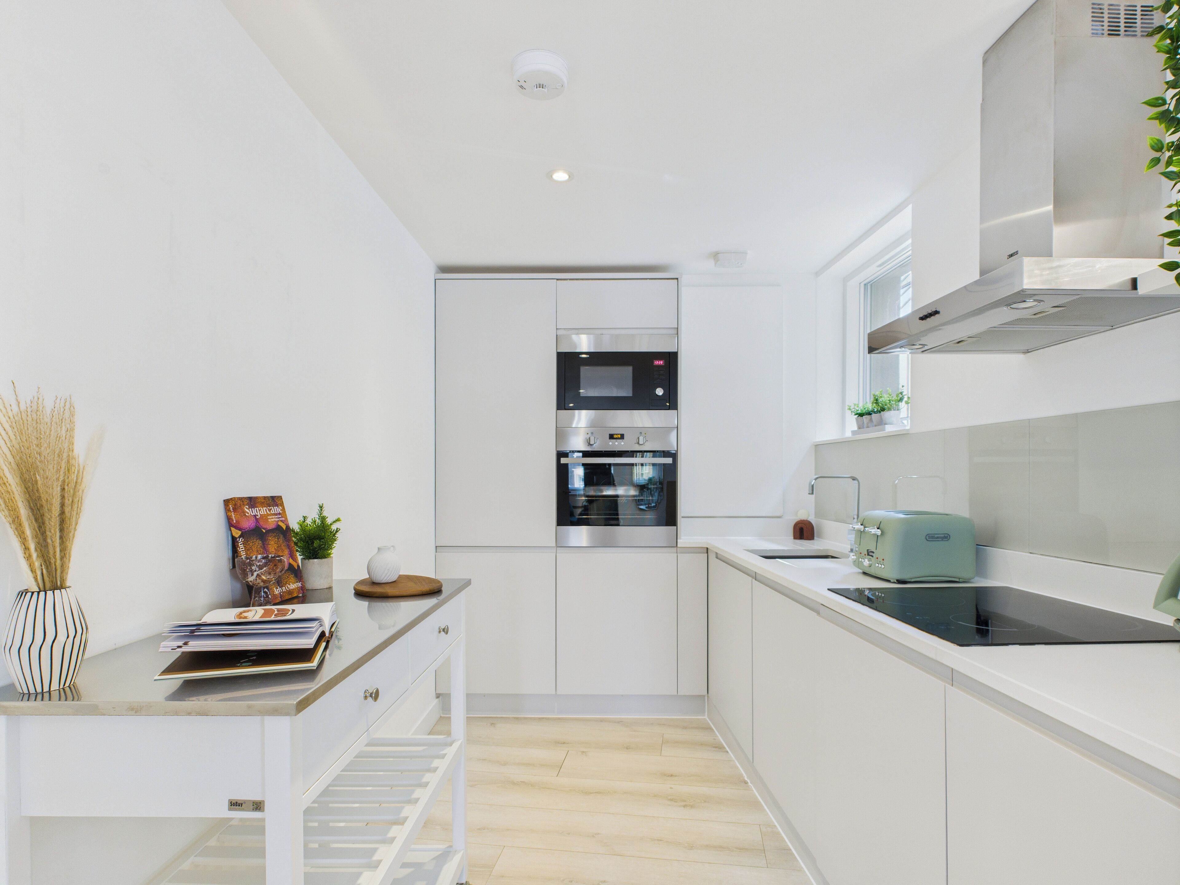 A modern kitchen with white cabinetry, a built-in oven, and a toaster.