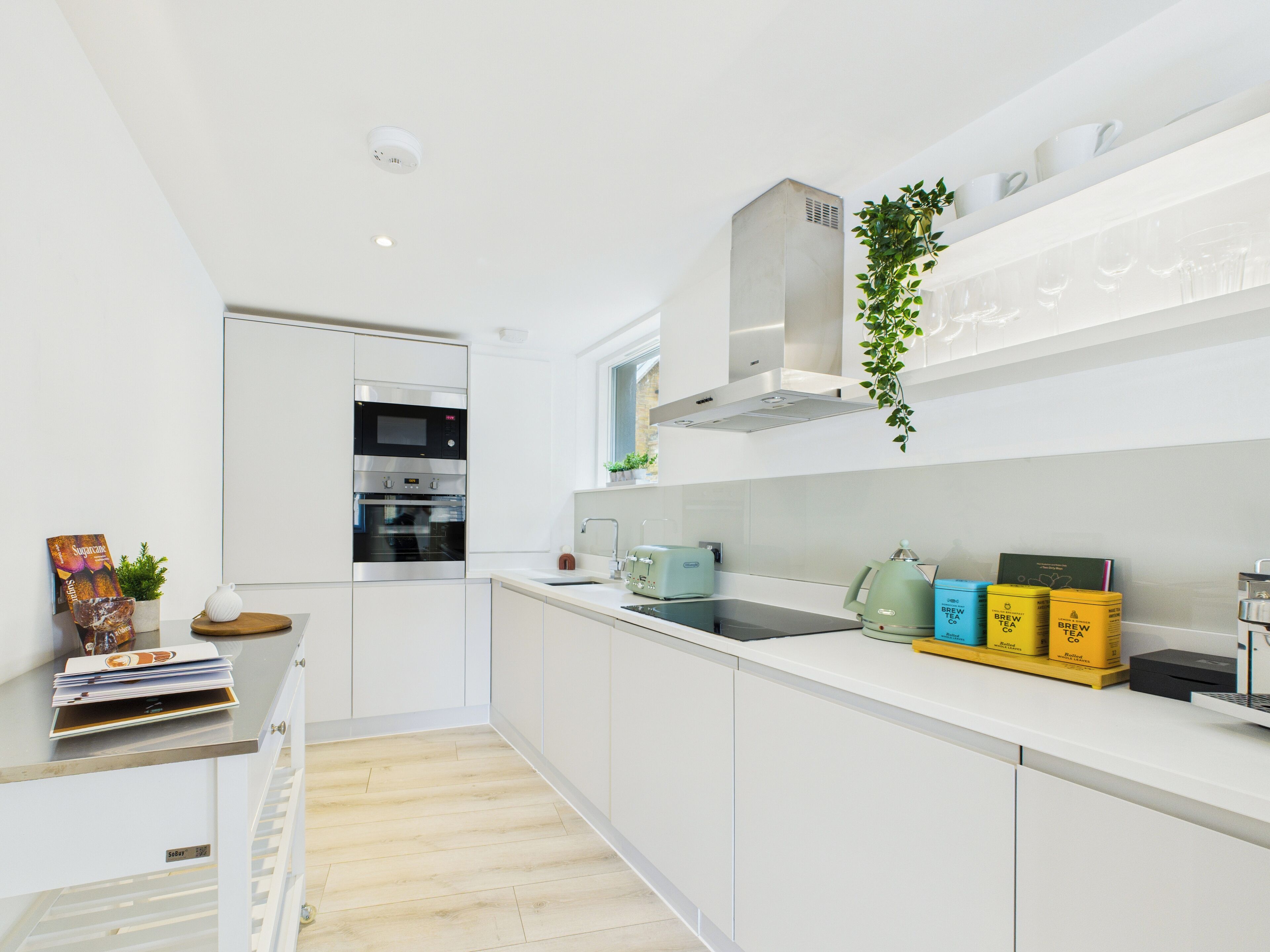 A modern kitchen with white cabinetry, a built-in oven, and a stainless steel range hood.