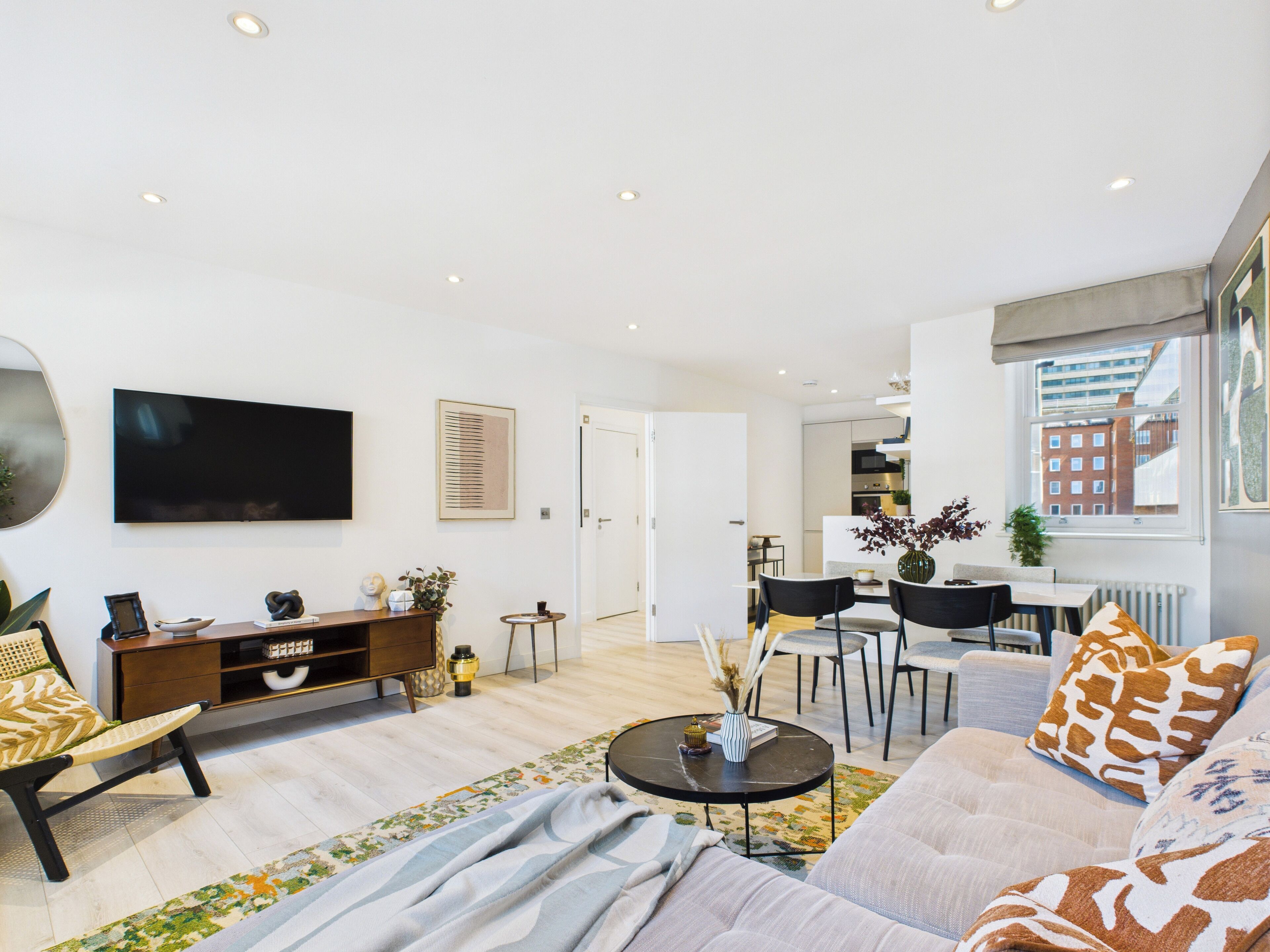 A modern living room with a sofa, coffee table, and a TV mounted on the wall.