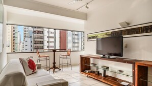 A modern living room with a sofa, a TV, a wooden entertainment unit, and a dining table with chairs. - Beachfront apt BC Center Close to Attract. Aco803 (Balneário Camboriú)