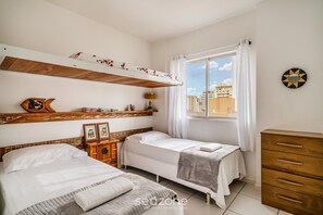 A bedroom with two beds, a wooden dresser, a window with curtains, and a wall clock. - Beachfront apt BC Center Close to Attract. Aco803 (Balneário Camboriú)