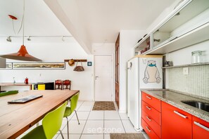 A kitchen with a wooden table, green chairs, a red cabinet, and a refrigerator with a bear design. - Beachfront apt BC Center Close to Attract. Aco803 (Balneário Camboriú)