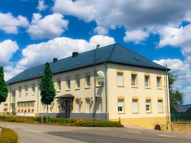 A two-story building with a flat roof, multiple windows, and a sign indicating it is a hotel.