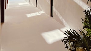 Un couloir aux murs blancs, avec une lucarne et une vue sur le ciel.