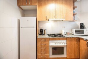 A compact kitchen with a refrigerator, microwave, stove, and oven.