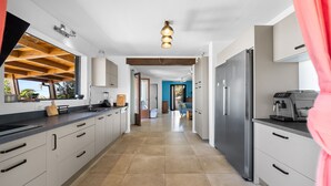 Una cocina moderna con armarios blancos, un refrigerador de acero inoxidable y una cafetera.