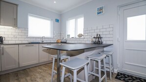Una cocina moderna con armarios blancos, una isla de encimera negra y taburetes de bar.