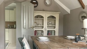 Un comedor con una mesa de madera, sillas y un armario con puertas de cristal.