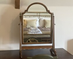 A mirror with a wooden frame on a table.