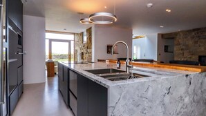 A modern kitchen with a marble countertop, stainless steel appliances, and a stone accent wall. - Carden Laithe Barn (Skipton)