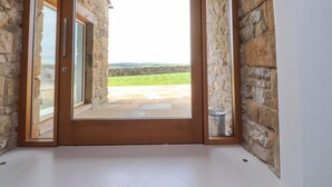 A room with a large sliding glass door leading to an outdoor area with a stone wall and a grassy lawn. - Carden Laithe Barn (Skipton)