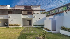 A two-story building with a flat roof, a small balcony, and a paved courtyard with a cactus plant. - House in Cabo Frio 200m From the Beach Adp001 (Cabo Frio)