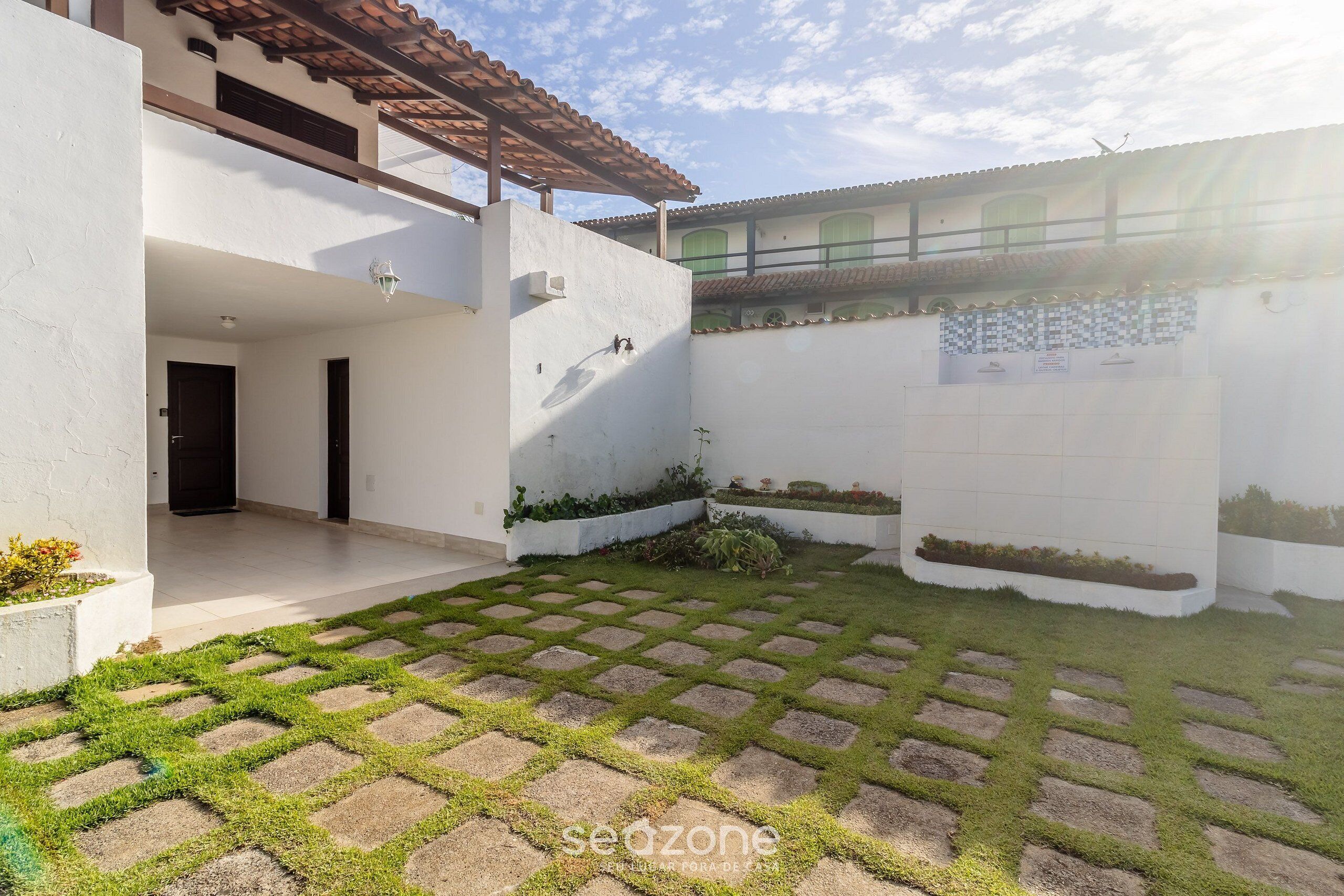 Un patio con suelo empedrado y un edificio blanco con techo de tejas.