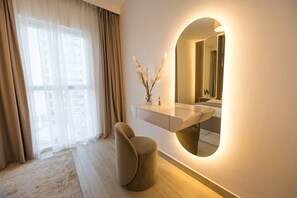 A modern bathroom with a vanity, a round mirror, and a window with curtains.