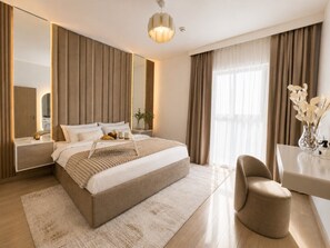 Une chambre d’hôtel moderne avec un grand lit, un coin salon, un bureau et un grand miroir.