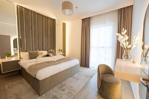 Ein modernes Hotelzimmer mit einem großen Bett, Nachttischen, einem Schreibtisch und einem Sessel.