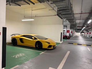 A yellow sports car parked in a multi-level parking garage with visible signage and a clean, industrial interior.