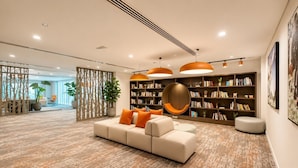 Un'accogliente hall moderna con un divano componibile, scaffali e una parete decorativa.
