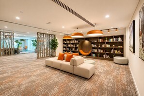 Ein stilvoller Lounge-Bereich mit einem Ecksofa, Bücherregalen und einer Wanddekoration.