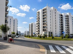 Een moderne stadsweg met hoge wooneenheden, een voetgangersoversteek en pijlen.