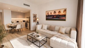 A modern living room with a sofa, coffee table, and dining area. - 1BDR F1 Yas Island | Stunning Views on the Circuit (Abu Dhabi)
