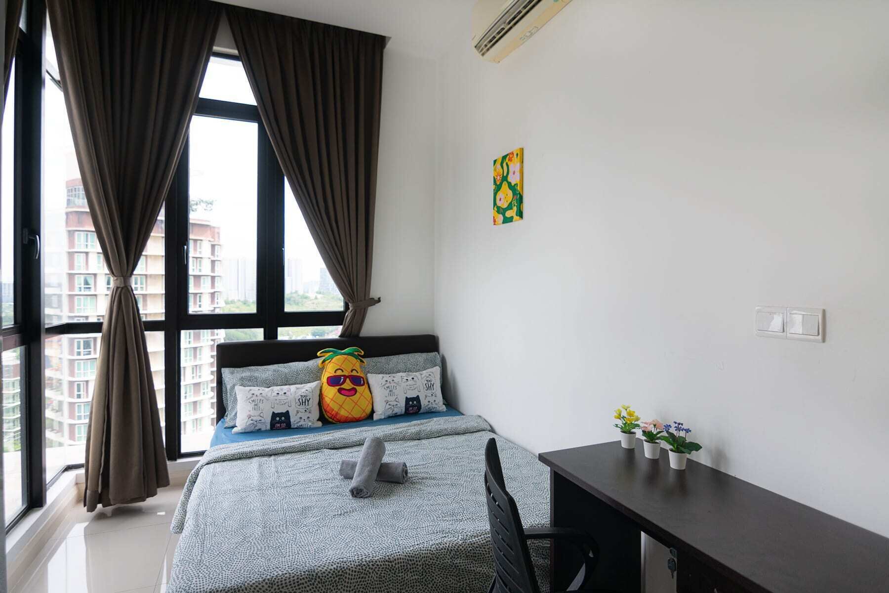 A bedroom with a bed, a desk, and a window with curtains.