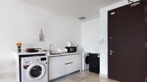 A compact kitchen with a washing machine, a microwave, and a sink. - Lovely Studio Trefoil Near Setia City Mall & Sccc (Shah Alam)
