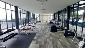 A gym with cardio machines, weight benches, and dumbbells. - Lovely Studio Trefoil Near Setia City Mall & Sccc (Shah Alam)