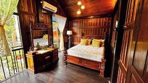 A wooden bedroom with a bed, bedside table, lamp, and a view of the outdoors.