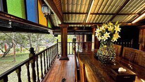 A wooden bar with a view of a garden, a decorative vase with flowers, and a traditional lantern.
