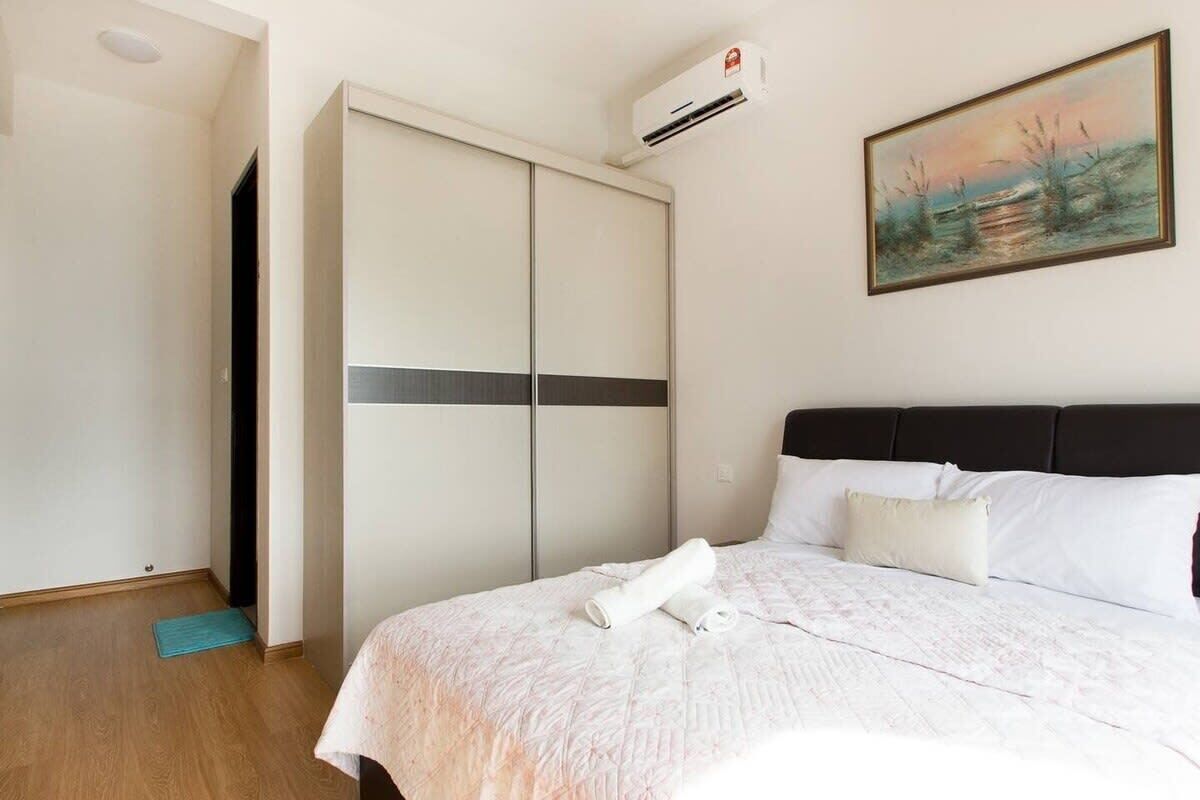 A hotel room with a bed, a wardrobe, an air conditioning unit, and a painting on the wall.