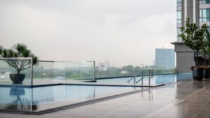 Ein Hallenbad mit Glasgeländern, einer Palme und Blick auf entfernte Gebäude.