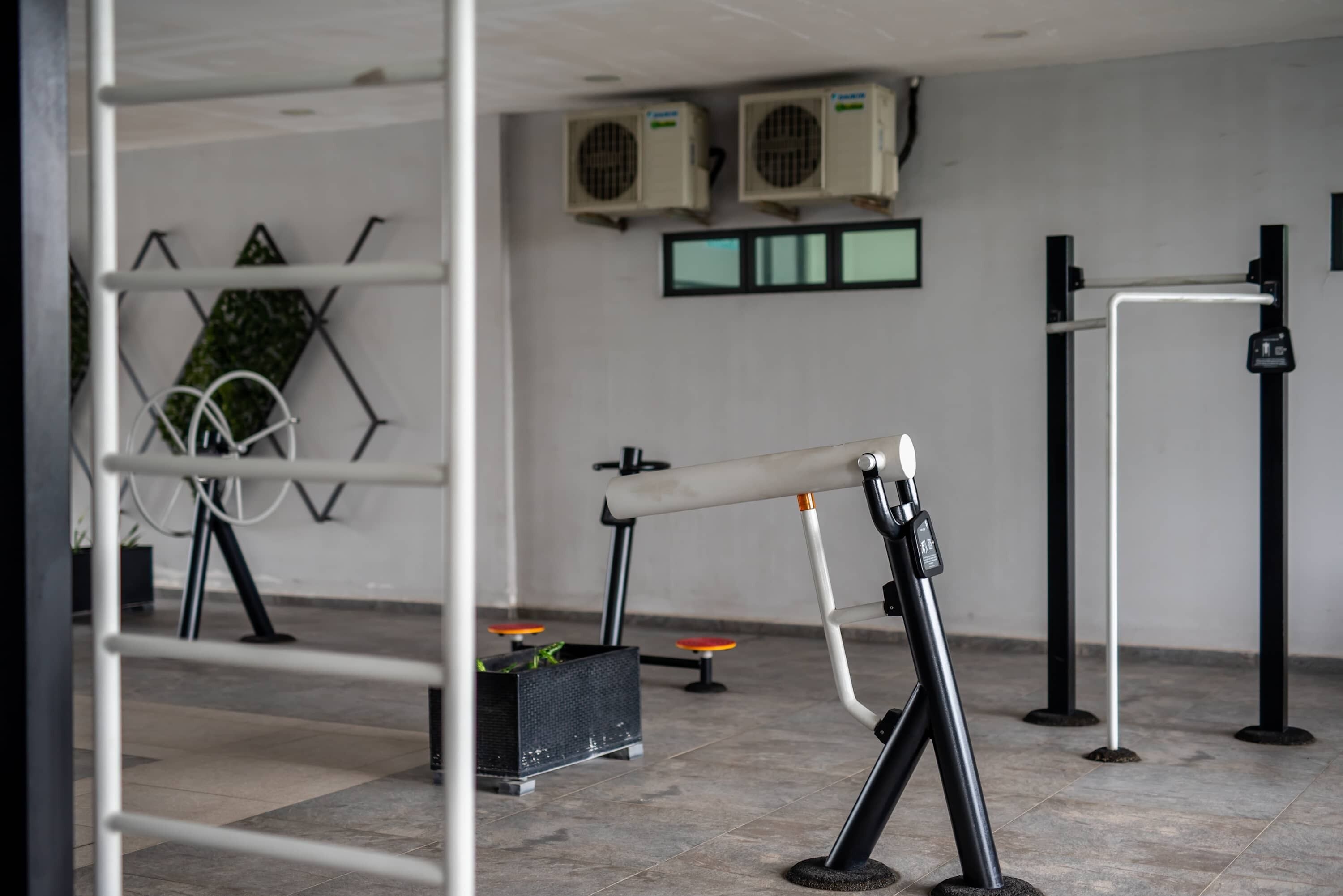 A gym with exercise equipment, air conditioning units, and a wall-mounted rack.