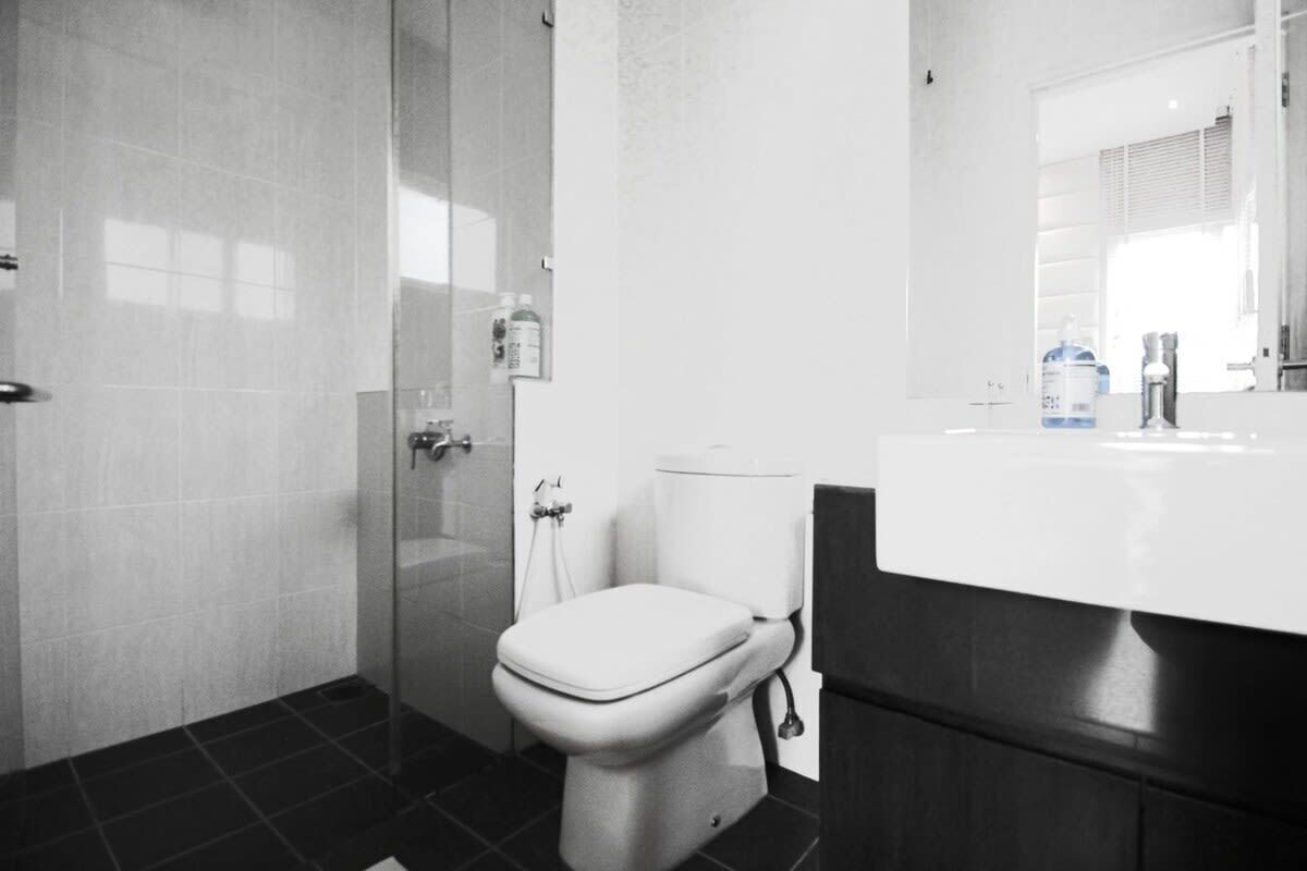 A bathroom with a toilet, a glass shower enclosure, and a white sink with a mirror above it.