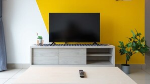 Ein modernes Wohnzimmer mit einem Flachbildfernseher auf einer weißen Unterhaltungsecke vor einer gelben Wand.
