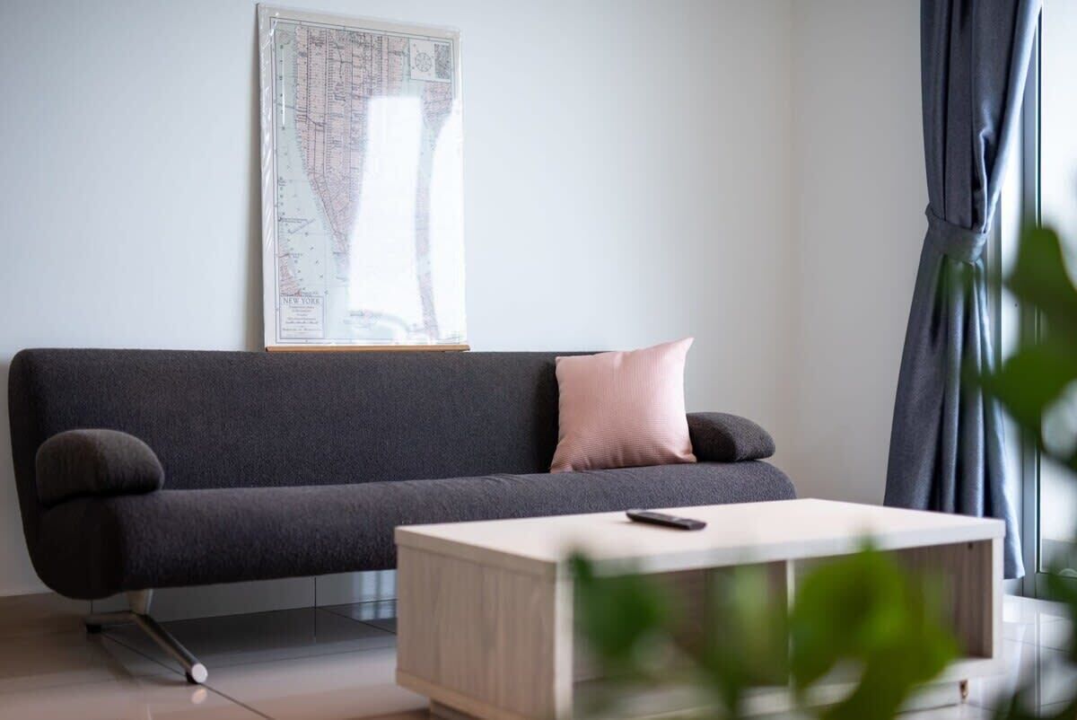 A modern living room with a dark grey sofa, a light wooden coffee table, and a map on the wall.