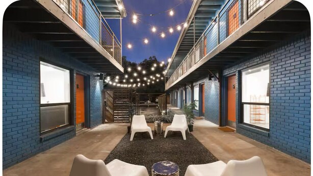 An outdoor seating area with brick walls, white chairs, and string lights. - H-Town Golden Bird Chic Lg Studio 10 the Best of Montrose (Houston)