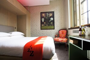 A hotel room with a bed, a chair, a desk with a mirror, and a window. - The Zetter (London)