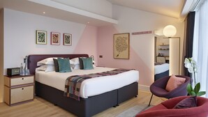 A modern bedroom with a large bed, bedside tables, a chair, and artwork on the walls. - The Zetter (London)