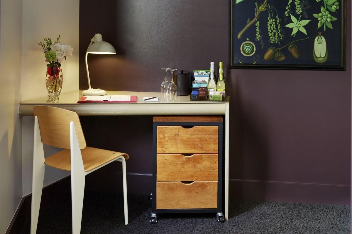 A modern room with a desk, chair, TV, and a botanical illustration on the wall.