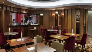 A restaurant with round tables and red chairs, a bar area, and a patterned carpet. - The Zetter (London)