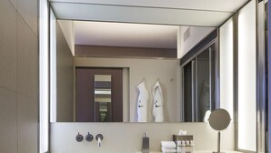 A modern bathroom with a large mirror, a toilet, and built-in shelves for towels. - The Zetter (London)